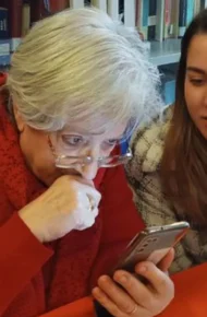 Nonna allo smartphone. Vicino a lei una ragazza le dà spiegazioni.